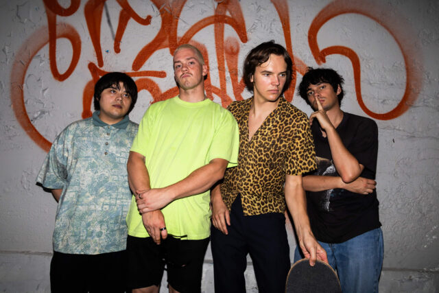 A scene from Mile End Kicks. Four indie band members in 2011 pose for a publicity photo against a graffitied wall.
